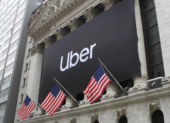 Uber logo on a building in New York with US flags handing in front of it.