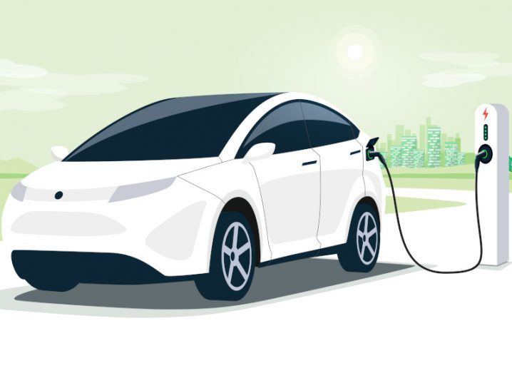 Cartoon of a white EV connected to a charging point with pale green sky.