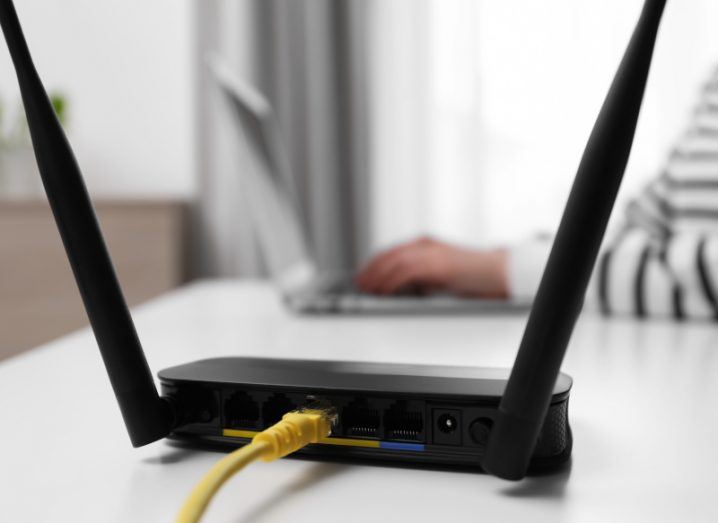 A broadband internet router with a person working on a laptop in the background.
