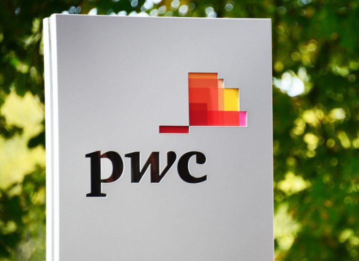 The PwC logo on a white column, with trees in the background.