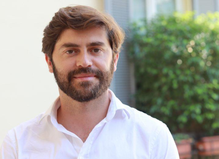 Headshot of Altin Kadareja, co-founder and CEO of Cardo AI, outside in front of a green hedge.