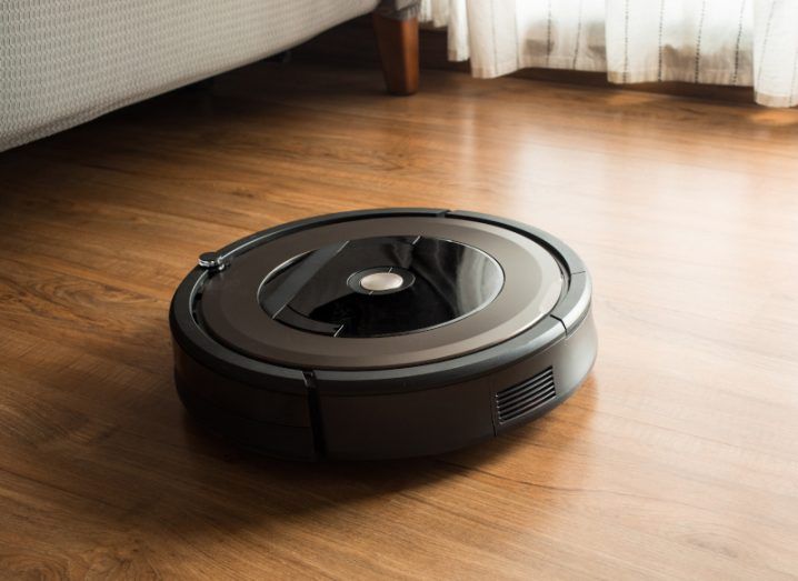 A Roomba vacuum on a hardwood floor.