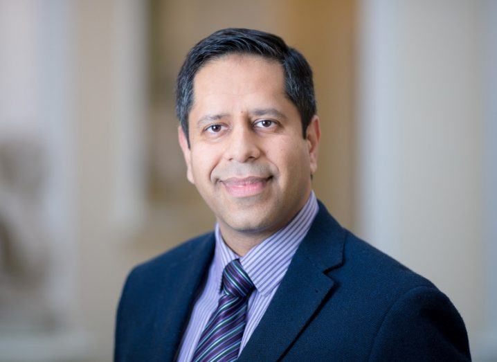 Headshot of Dr Aamir Hameed wearing a blue suit and tie with a blurred background.