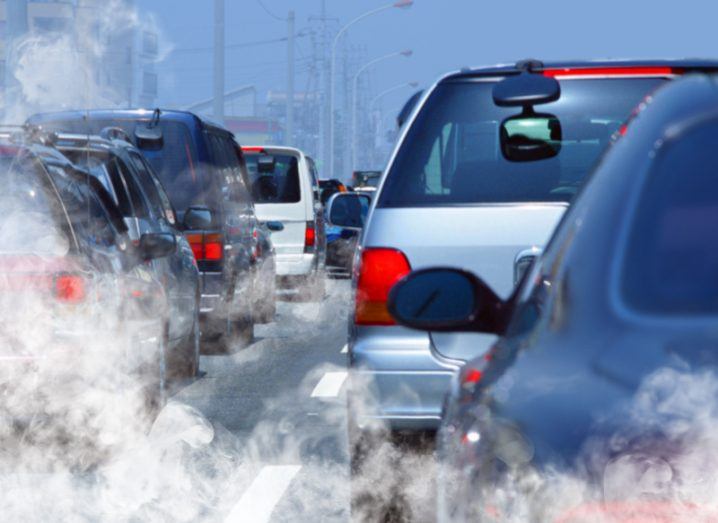 Cars stuck in a traffic jam with smoke from exhausts rising into the air.