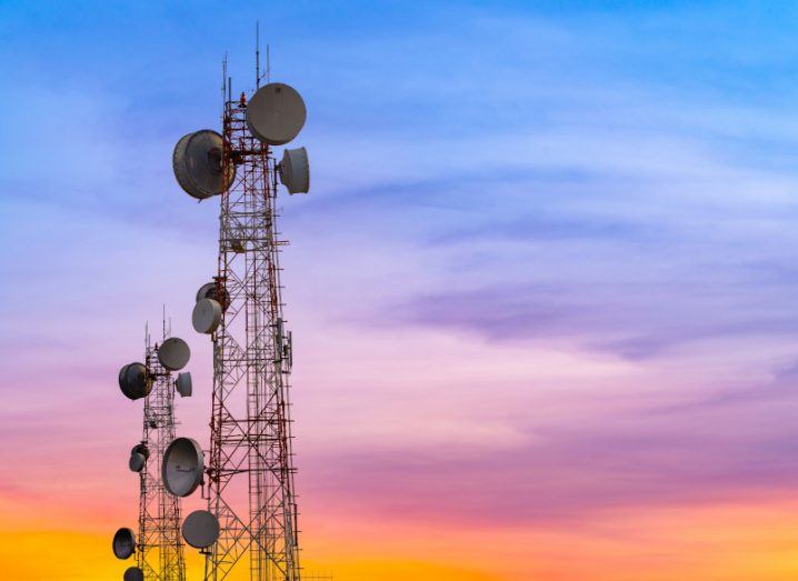 Two telecom towers stand against the backdrop of a sunset sky.