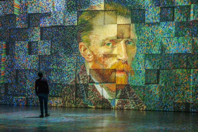 Van Gogh’s self-portrait on display at the exhibition with a person standing in front of it and staring.