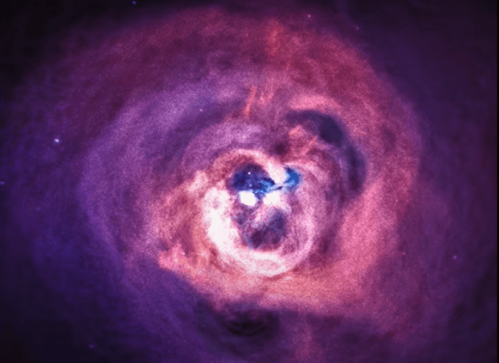 Image of a black hole at the centre of a purple galaxy cluster.