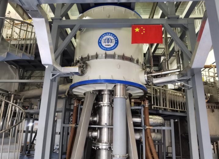A large grey machine with a Chinese flag next to it, inside a lab. It is a hybrid magnet.