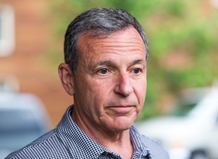A man in a grey shirt with a blurred tree and cars in the background. He is Bob Iger, Disney CEO.
