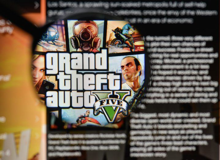 A magnifying glass held up to a screen showing the Grand Theft Auto logo.