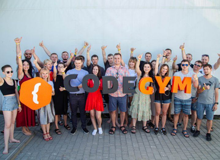 In a large group of people, those in front are holding up letters spelling out CodeGym while the rest have their hands in the air giving the thumbs up sign.