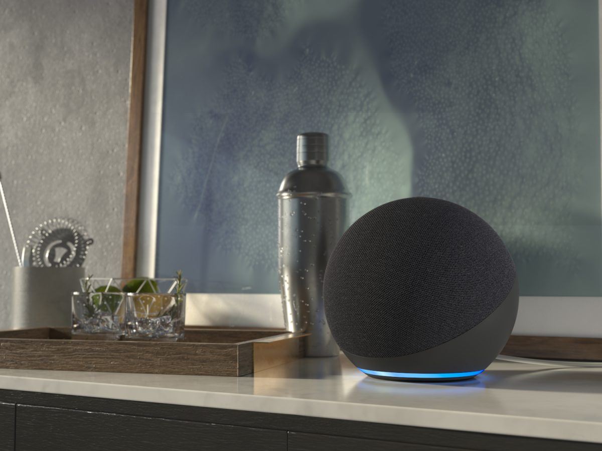 An Amazon Echo speaker resting on a table with a painting in the background.