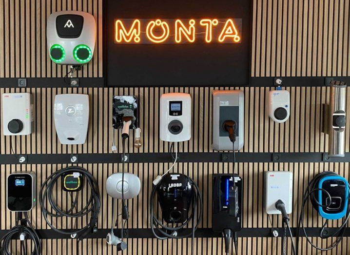 Monta logo in neon letters on a wall with EV chargers attached to it.