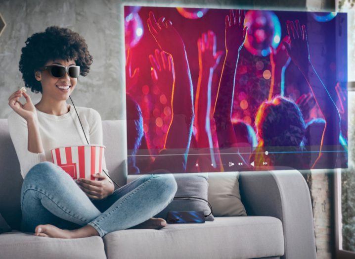 Woman sitting on her couch streaming TV using Lenovo Glasses T1.