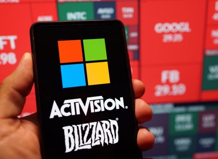 Microsoft and Activision Blizzard logos on a smartphone screen held in a person's hand.