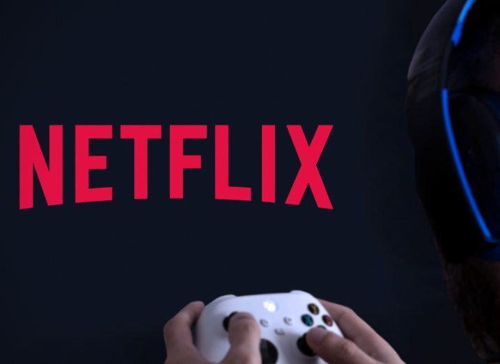Person holding a controller and pointing it at a screen that has the Netflix logo on it.