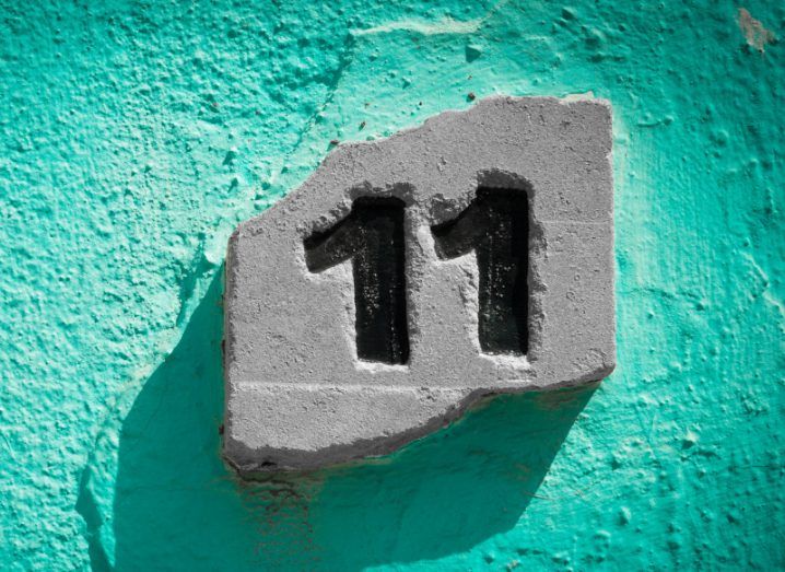 The number 11 carved into a white stone on an aquamarine wall.