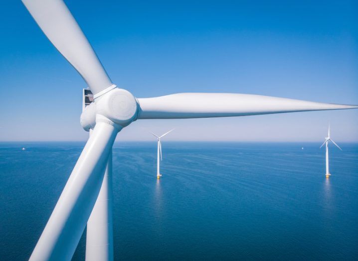 Close up of an offshore wind turbine with other wind turbines visible in the background.