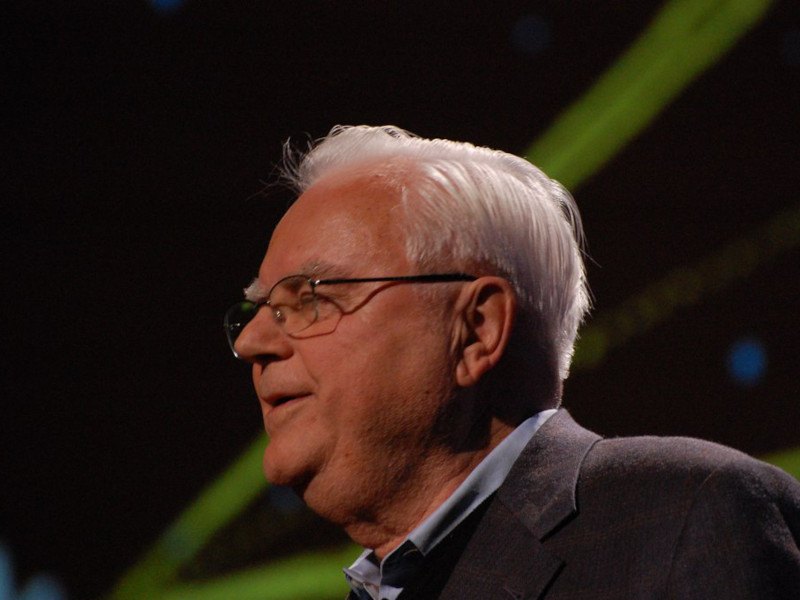 A close-up shot of Frank Drake speaking from a stage.