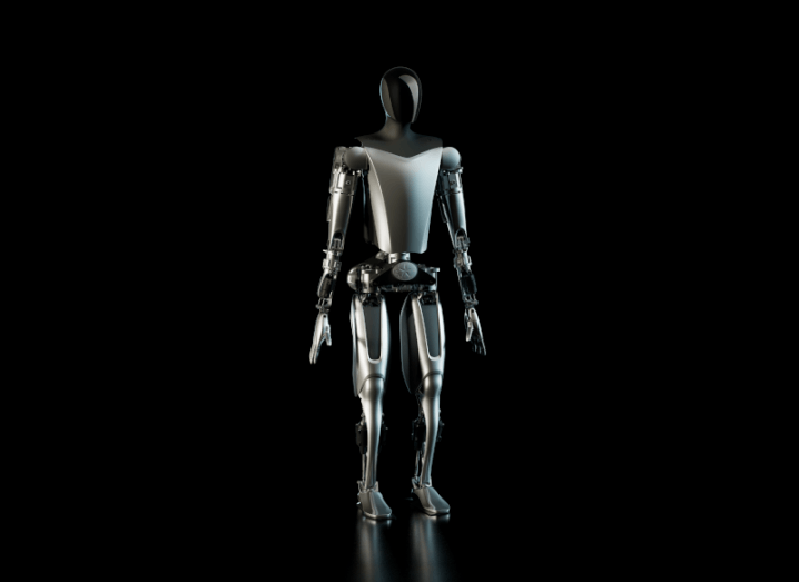 A Tesla Optimus humanoid robot, standing in a black background.