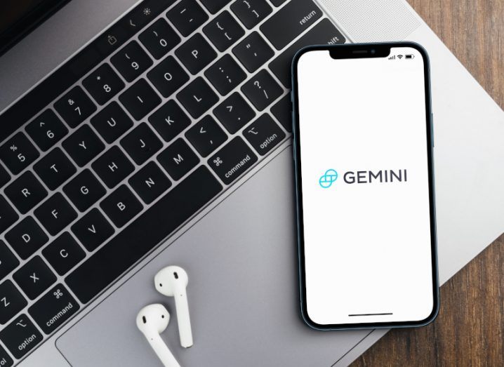 Gemini crypto app open on a smartphone with airpods and a laptop.