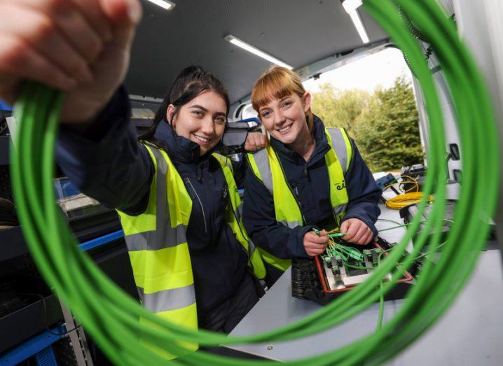 Two women in high visibility vests with one holding a circle of fibre cables. They are Open Eir technicians Sarah Doyle and Isobelle McSweeney.
