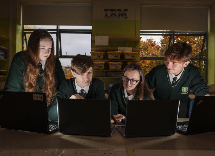 Four Dublin students sit around computers with the IBM logo on the wall in the background.