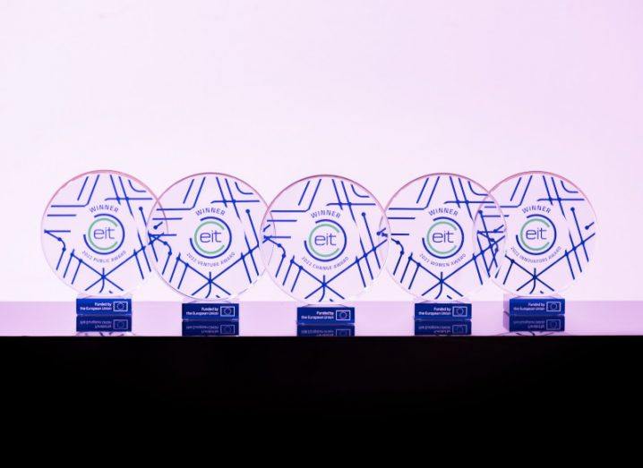 Five disc-shaped awards trophies are lined-up on a brightly lit stage.