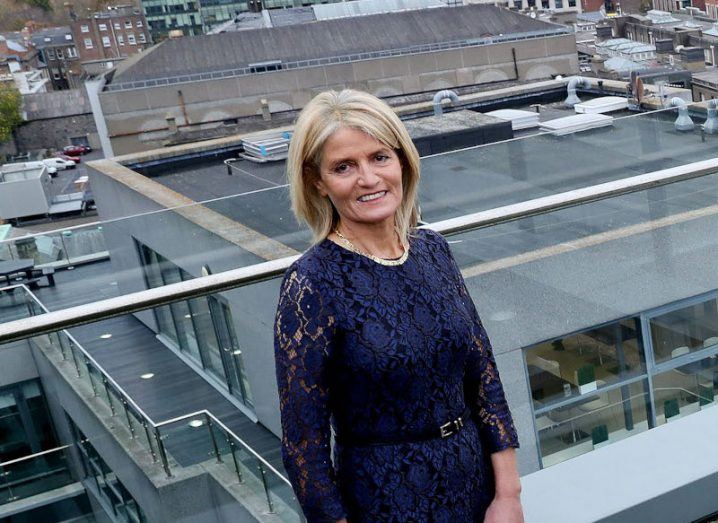 A woman standing on a roof with other buildings in the background. She is Mary Buckley, interim CEO of IDA Ireland.