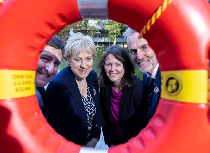 Two men and two women smiling through the circle of a ring buoy.