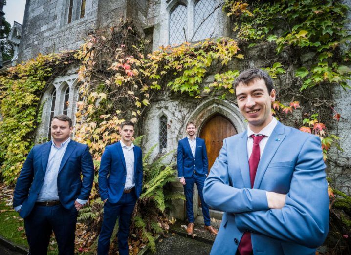 Photo of four young men wearing suits standing in front of an ivy-covered building in UCC during the Ignite awards.
