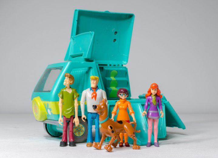 Scooby-Doo toy characters including Velma with a toy Mystery Machine van behind them.