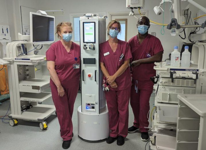 Three healthcare workers stand around a device from Akara Robotics.