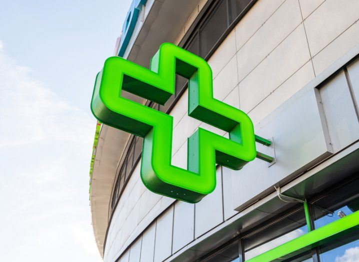 A green cross logo representing a pharmacy on the side of a building.