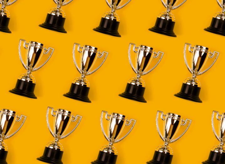 Gold trophy cups on a yellow-orange background.