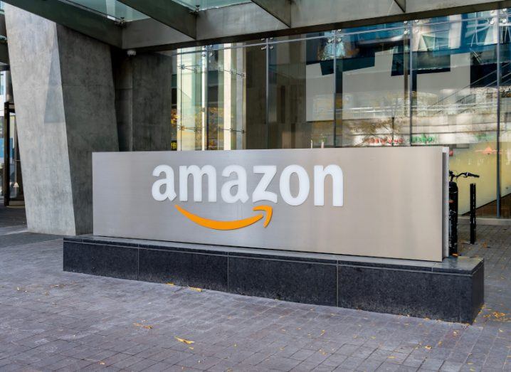 The Amazon logo on a grey ground sign in front of a building.