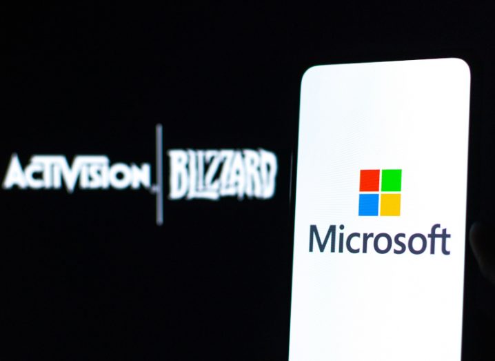 A phone with the Microsoft logo on the screen. In the background is the logo for Activision Blizzard.
