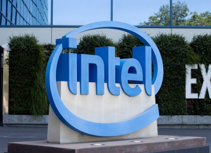 A blue Intel logo on a grey slab, in front of a windowed building.