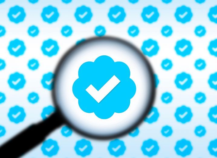 A magnifying glass over a zoomed in Twitter verified blue tick, with multiple blue ticks in the background.