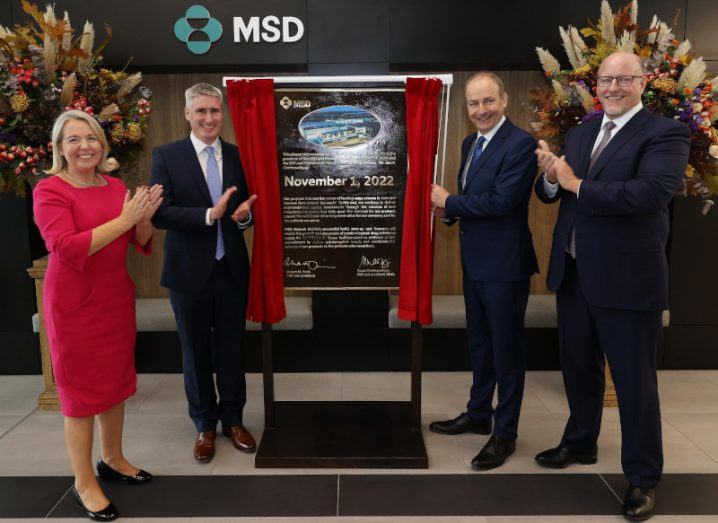 One woman and three men gathered around a plaque with details of MSD's biotech facility in Dublin on it.