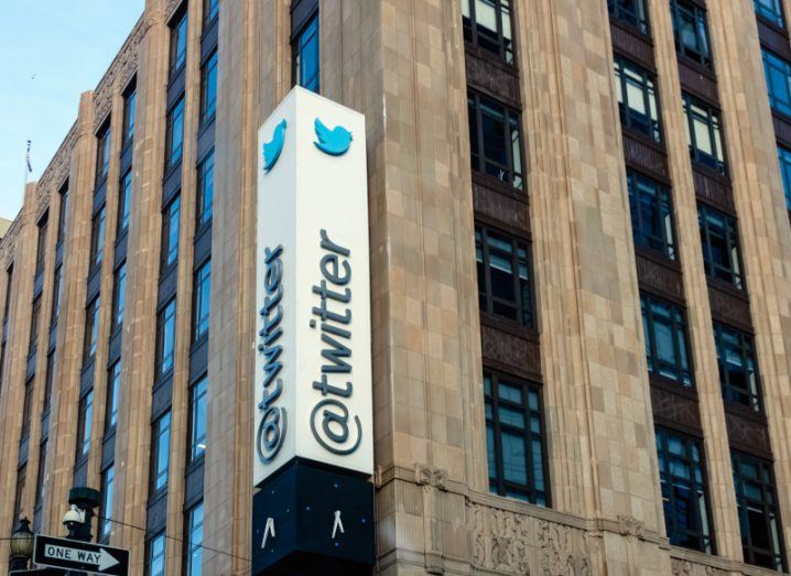 The Twitter logo on a vertical sign outside a building.
