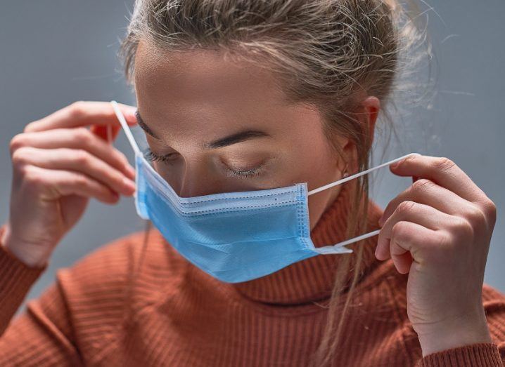 Woman putting a mask on, symbolising viral resistance.