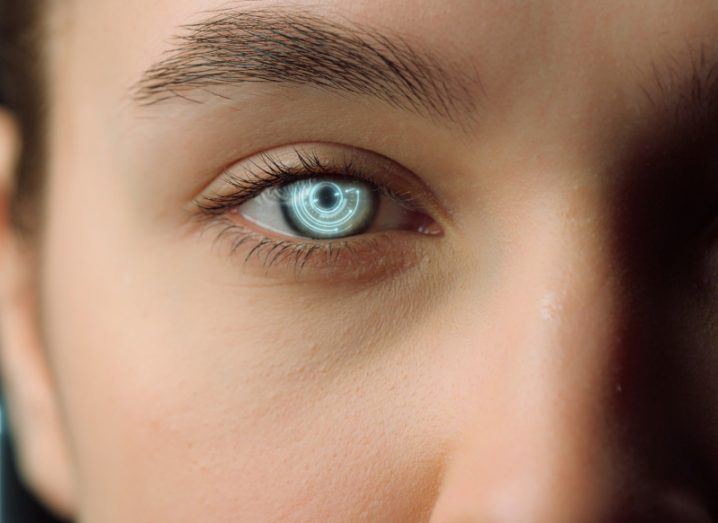 Close-up of one half of a woman's face with the pupil of the eye shining bright. Represents deepfakes.