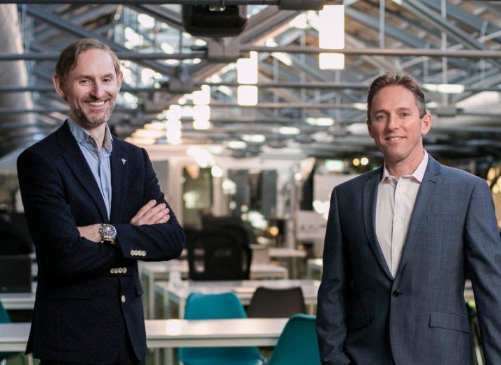 The co-founders of MedoSync standing next to each other wearing suits. They appear to be in an indoor office space.