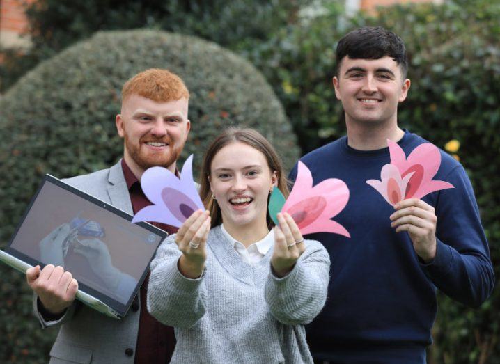 Photo of three MTU Cork students consisting of two boys and one girl in the centre. The girl and the boy on the right are holding paper cutouts in the shape of Tulips while the boy on the left is holding a laptop.