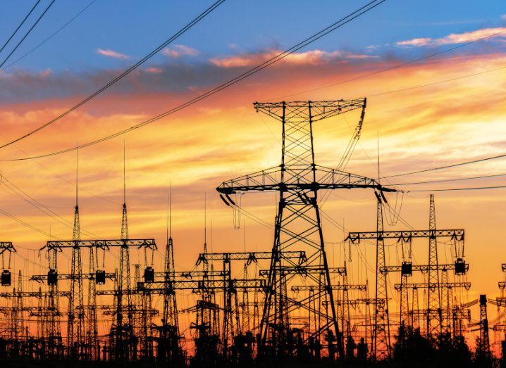 Electricity lines at a distribution station photographed during sunrise or sunset.