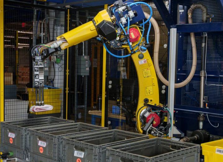 A yellow robotic arm called Sparrow sorting different items in an Amazon warehouse.