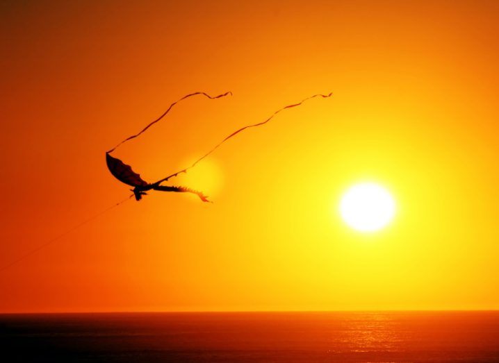 Photo of a kite in the sky with a sunset in the background.