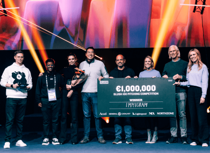 Immigram co-founder Anastasia Mirolyubova stands on stage at Slush surrounded by people, some of whom are holding up a large novelty cheque valued at €1m.