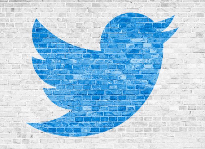 The Twitter logo on a white brick wall, with the parts of the logo coloured blue.